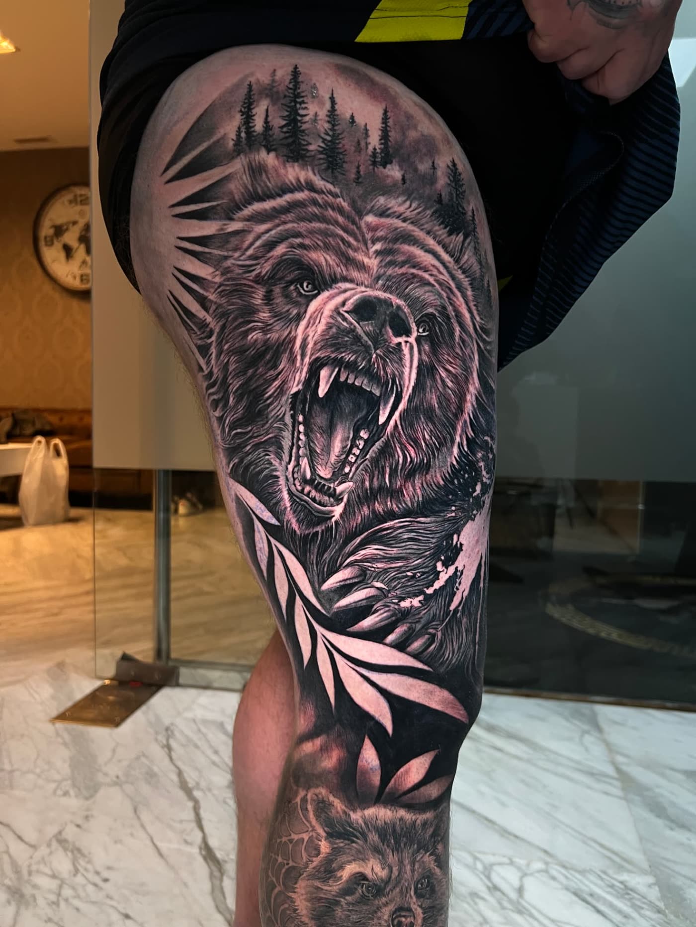 Tatuaje realista de oso con bosque en el muslo, black and grey, estudio de tatuajes en Almassora